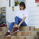 Red KAMON tabi shoes featuring a split-toe design, shown worn in a relaxed outdoor setting.