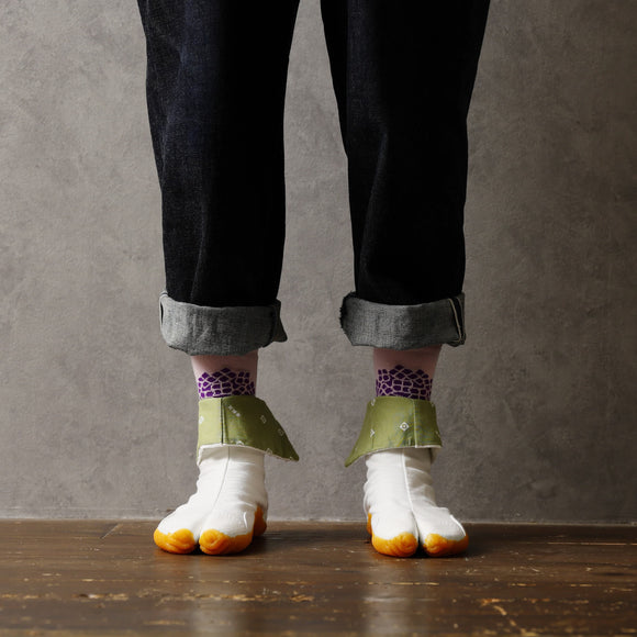 Person wearing long pink Tabi Socks 'Ajisai' with purple hydrangea pattern, paired with white Tabi Shoes 'SAIBU' featuring orange soles