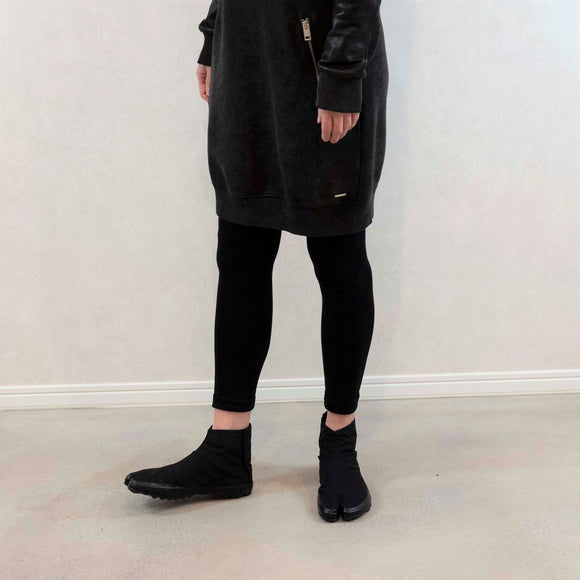 Person wearing black Tabi Shoes "U-ten" in a casual standing pose indoors
